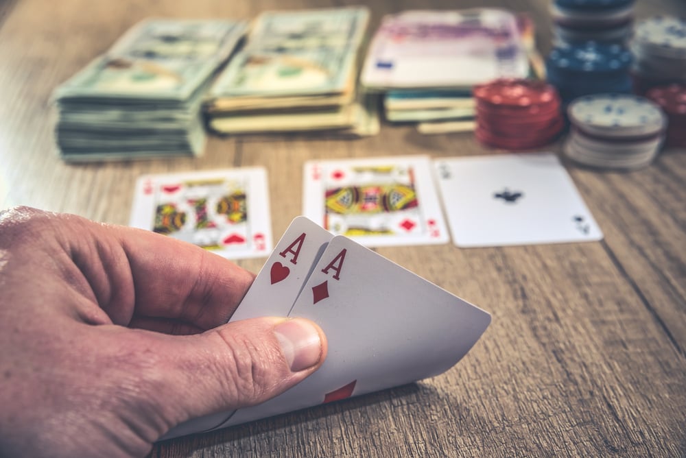 Poker player peeking at hole cards with stacks of cash and chips on table