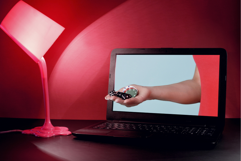 Hand with poker chips reaching out of laptop monitor