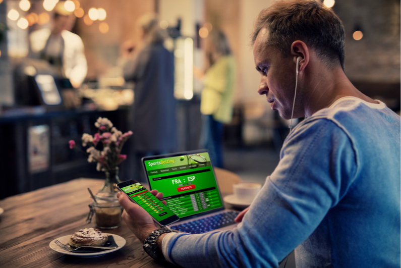 Man mobile betting on sports in a coffee shop